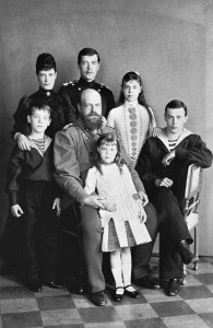 Aleksander III siedzi w środku trzymając stojącą wielką księżną Olgę. Po jego lewej stronie stoi wielki książę Michał, po prawej, ze skrzyżowanymi nogami siedzi wielki książę Jerzy. Z tyłu po lewej stoi caryca Maria Fiodorowna, dalej stoi carewicz Mikołaj, późniejszy cesarz Mikołaj II i wielka księżna Ksenia. Fot. 1888 r.